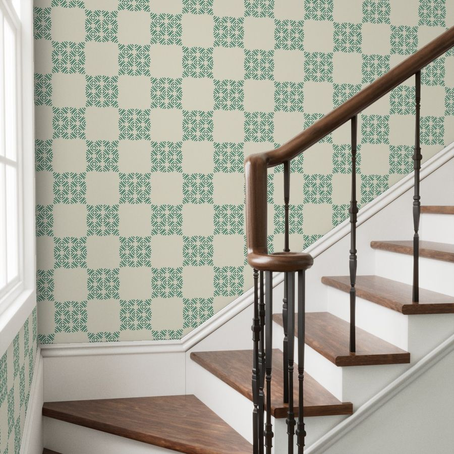 Staircase with wooden banister against a wall with green and white geometric patterned wallpaper.