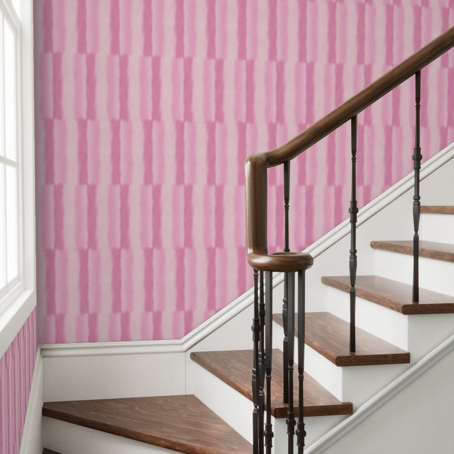 Staircase with wooden handrail against a pink patterned wall.