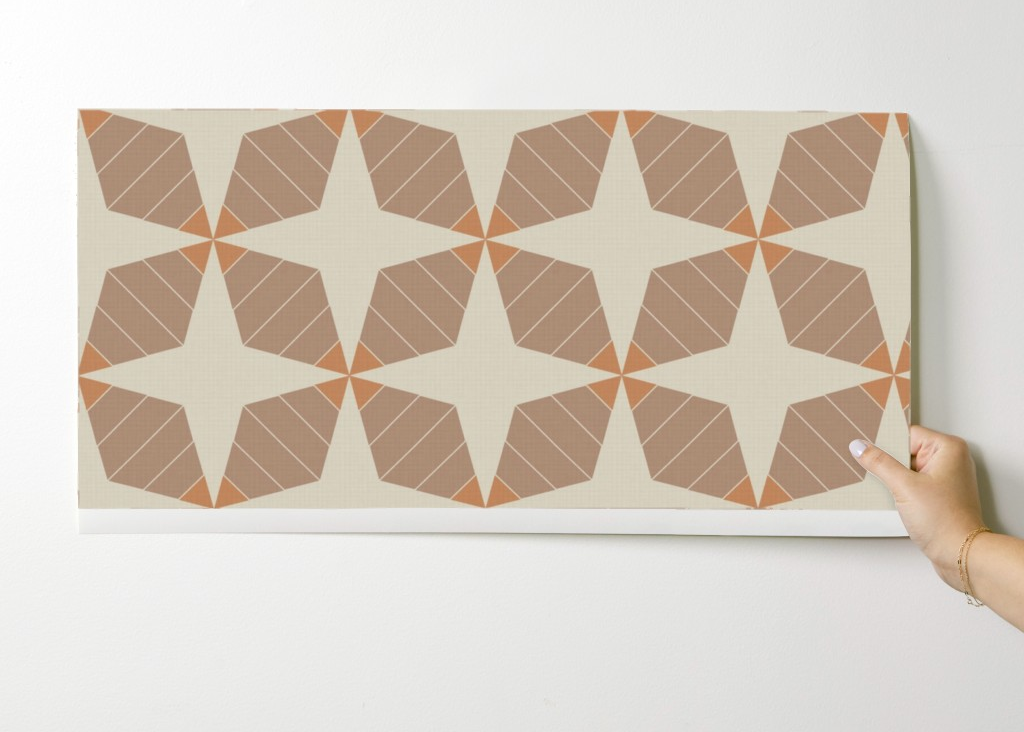 Hand holding a decorative tile with geometric pattern on a white background