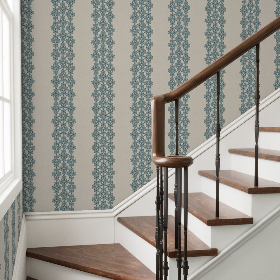 Staircase with wooden steps and a decorative railing against a wall with vertical patterned wallpaper.