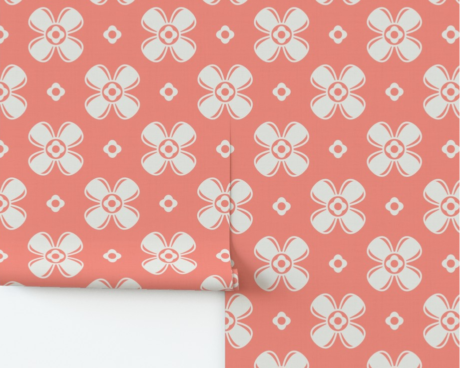 Roll of pink wrapping paper with white floral pattern on a wooden surface.